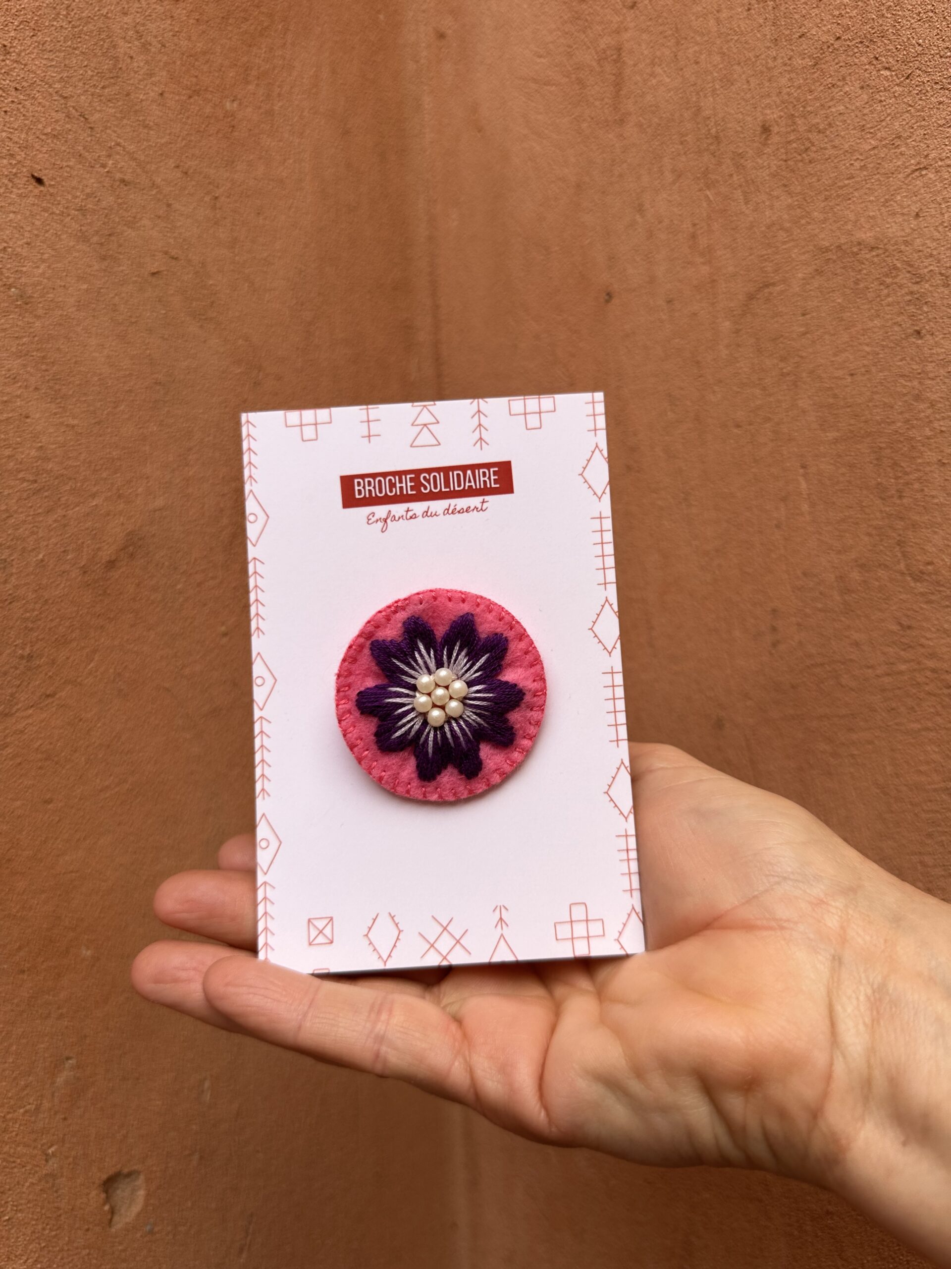 Broche en feutrine avec une fleure violette brodée.