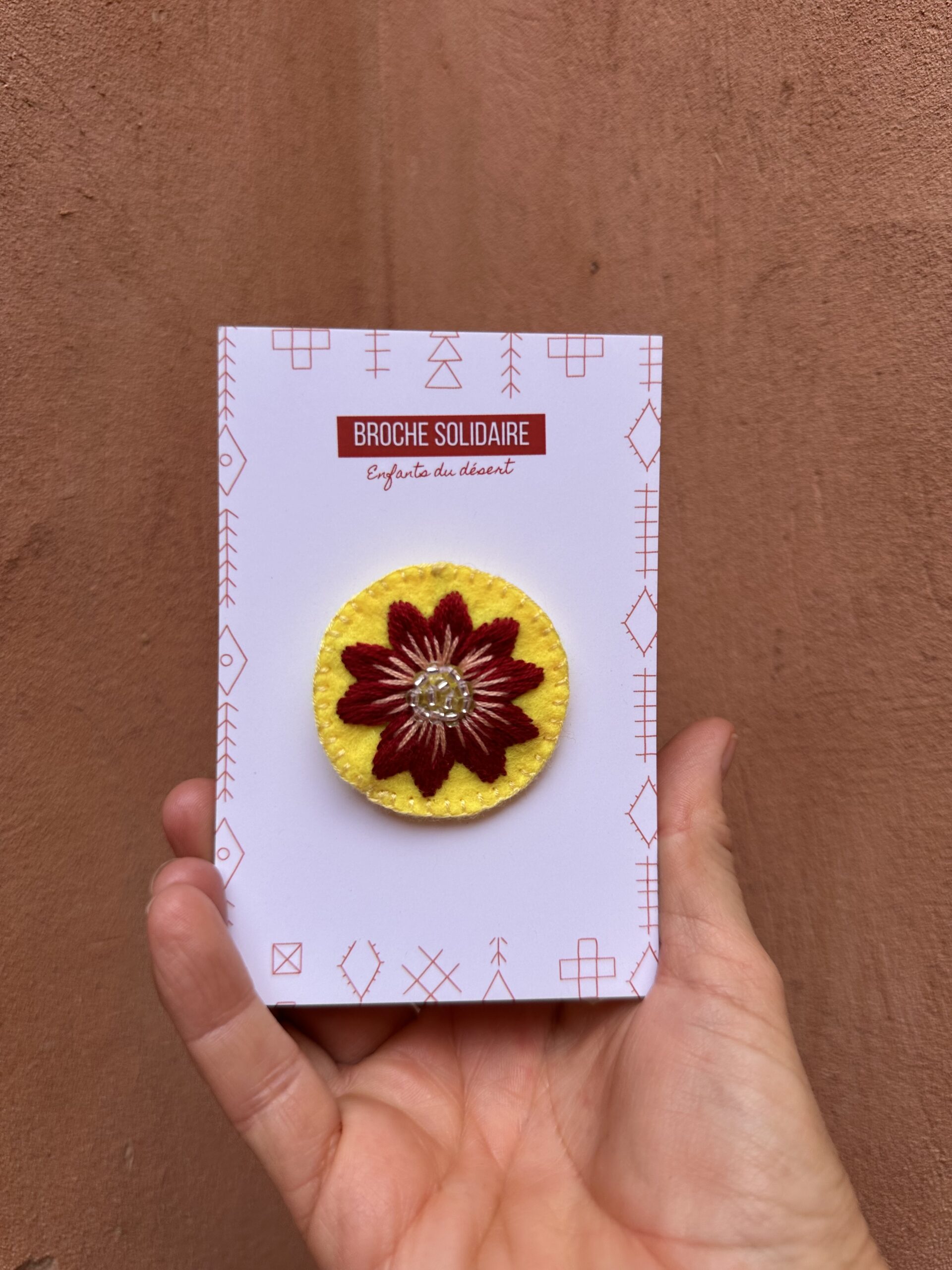 Broche en feutrine fleurie, jaune et rouge.