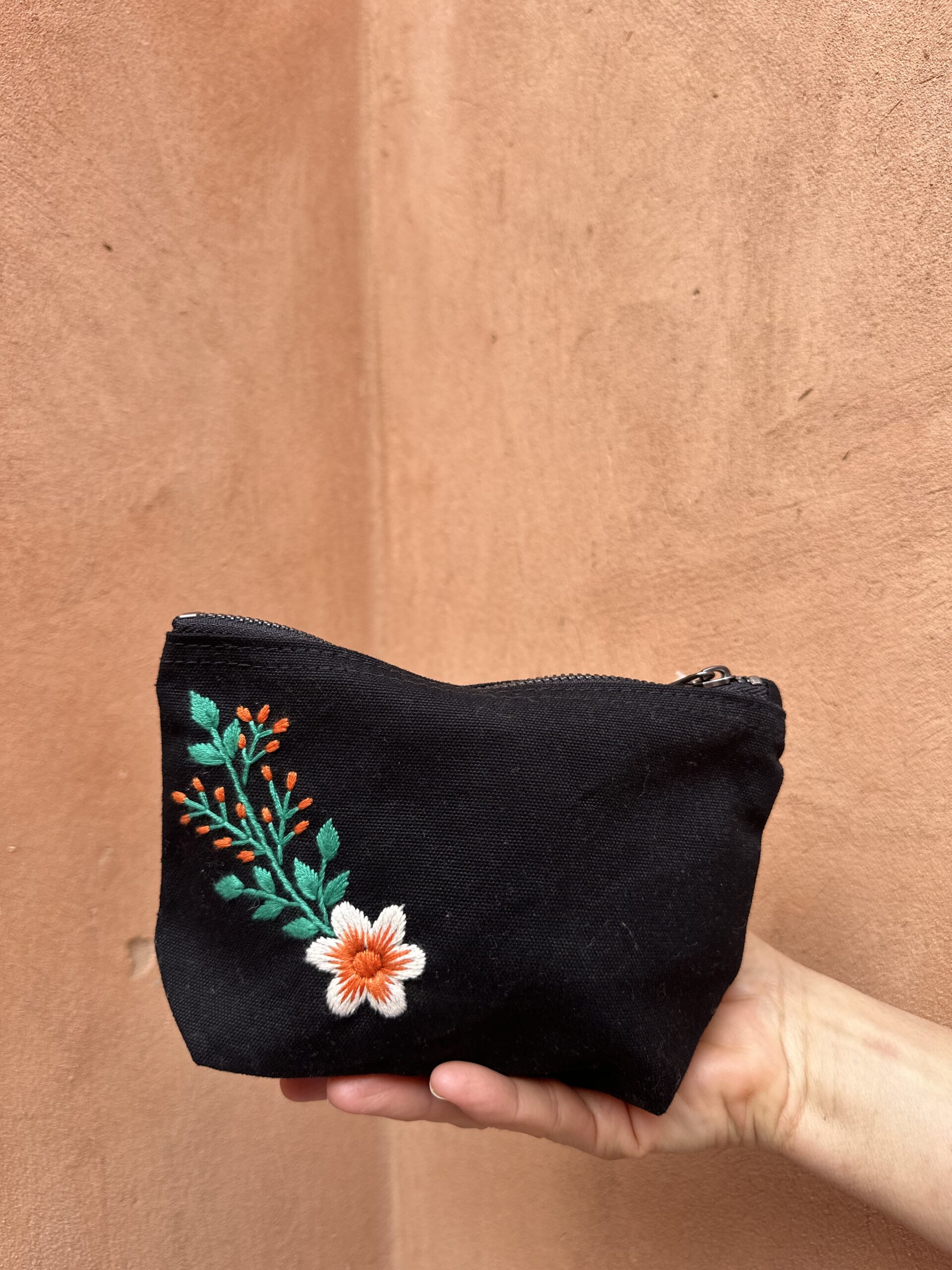 Pochette noire avec broderie à fleur.