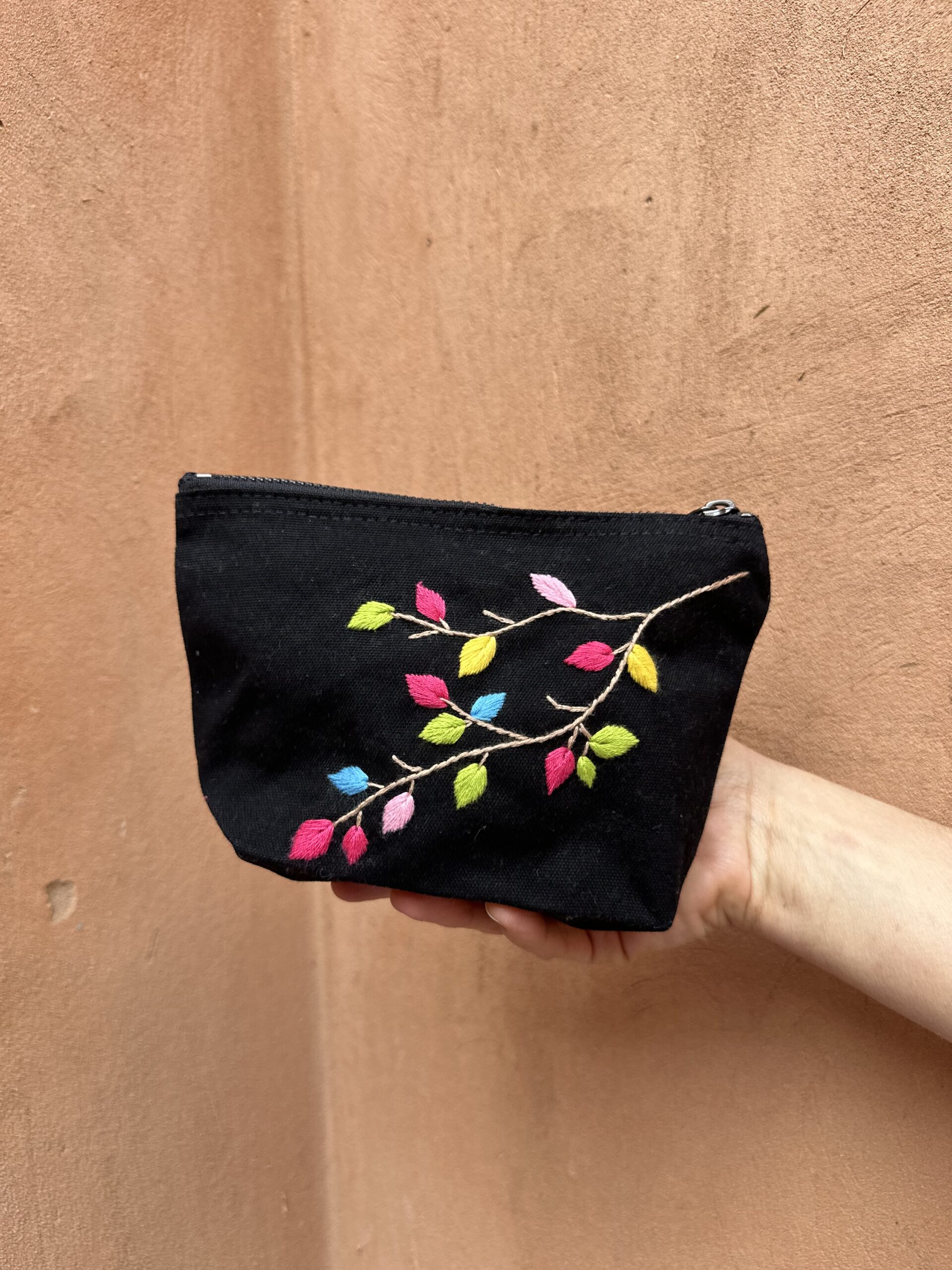 Pochette noire avec broderies de feuilles colorées.