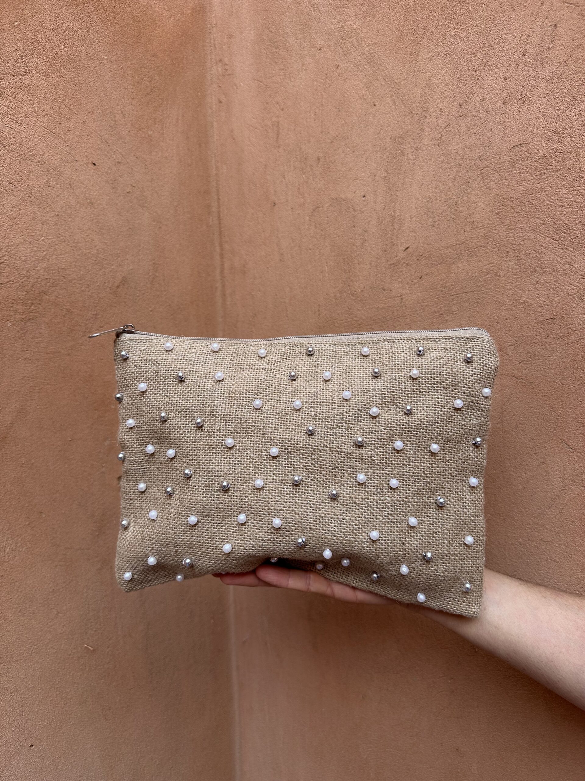 Pochette en jute brodée de perles blanches.