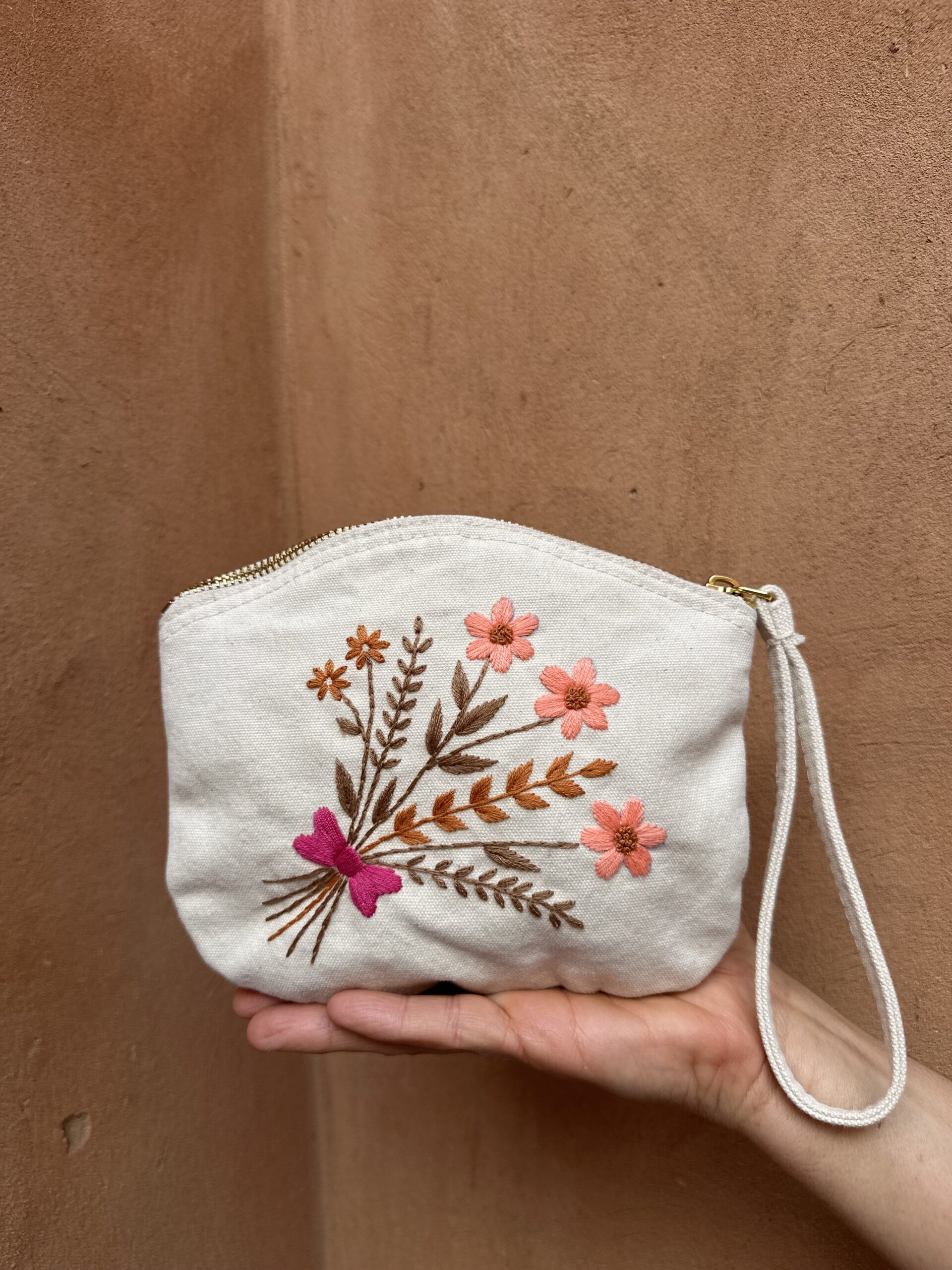 Pochette beige avec des broderies à fleurs.