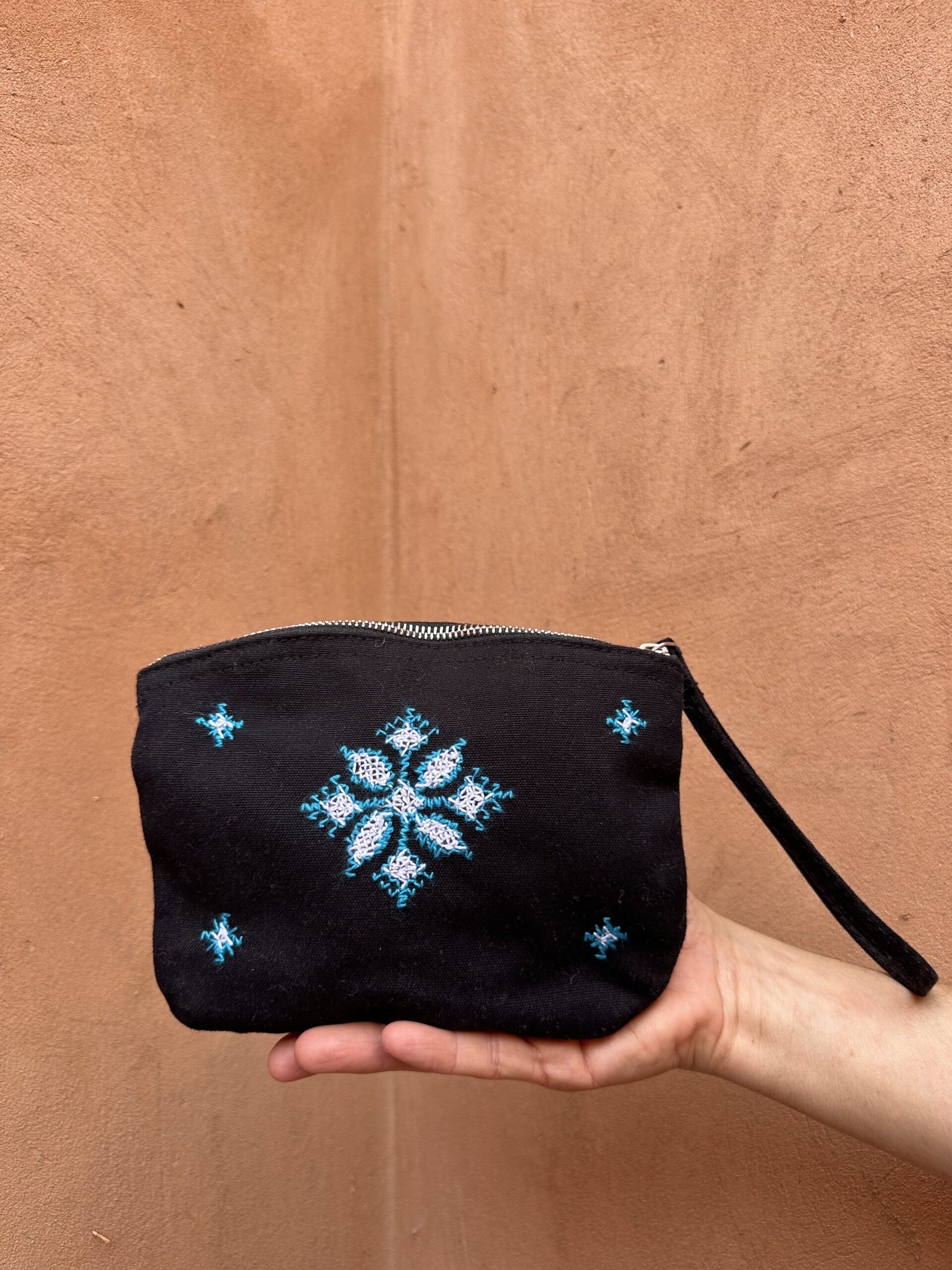 Pochette noire avec anse décorée de broderies inspiration berbère bleues.