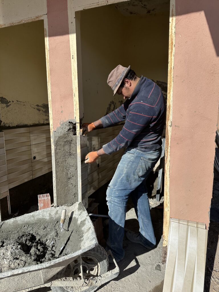 réhabilitation des murs des sanitaires par un ouvrier 