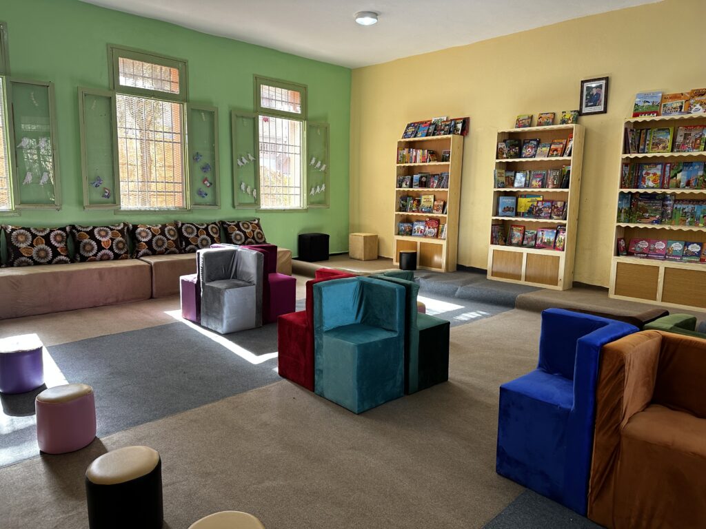 nouvelle bibliothèque avec étagères remplies de livres, fauteuils, canapés, tout en couleur