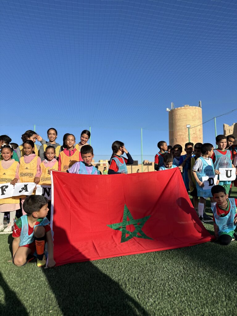 enfants déploient le drapeau marocain lors de l'inauguration du terrain de football de Rissani