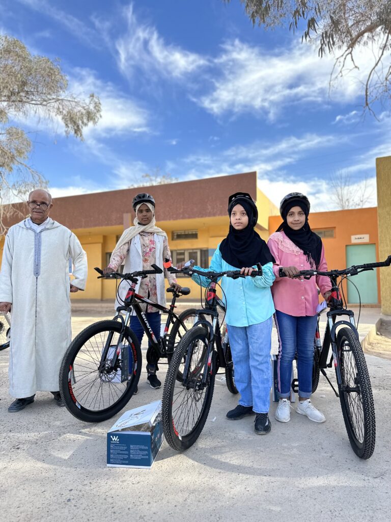 3 filles avec leurs nouveaux  vtt et un professeur d'école lors du don de vélos