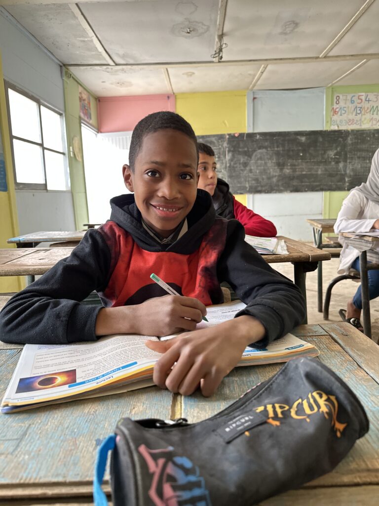 enfant sourit assis à son bureau