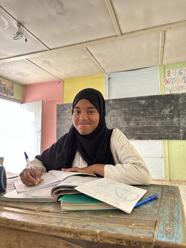 jeune fille sourit assise à son bureau